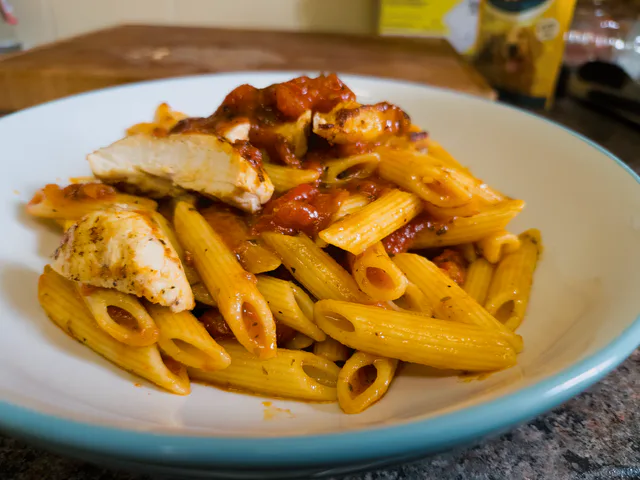 Chicken pizzaiola pasta served in a blue bowl.