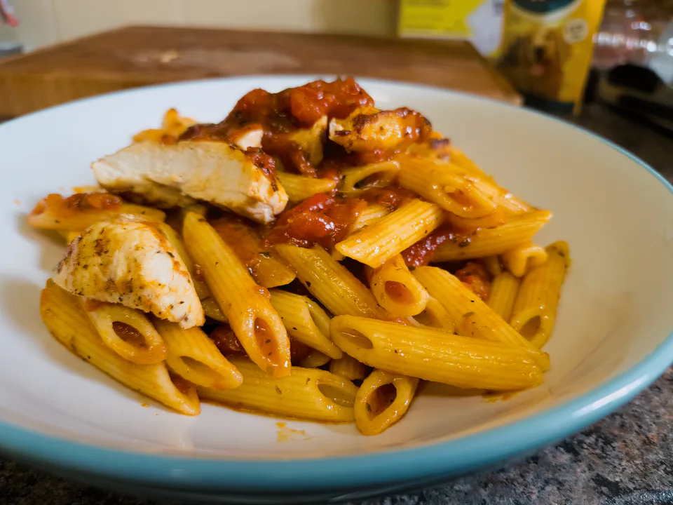 Chicken pizzaiola pasta served in a blue bowl.