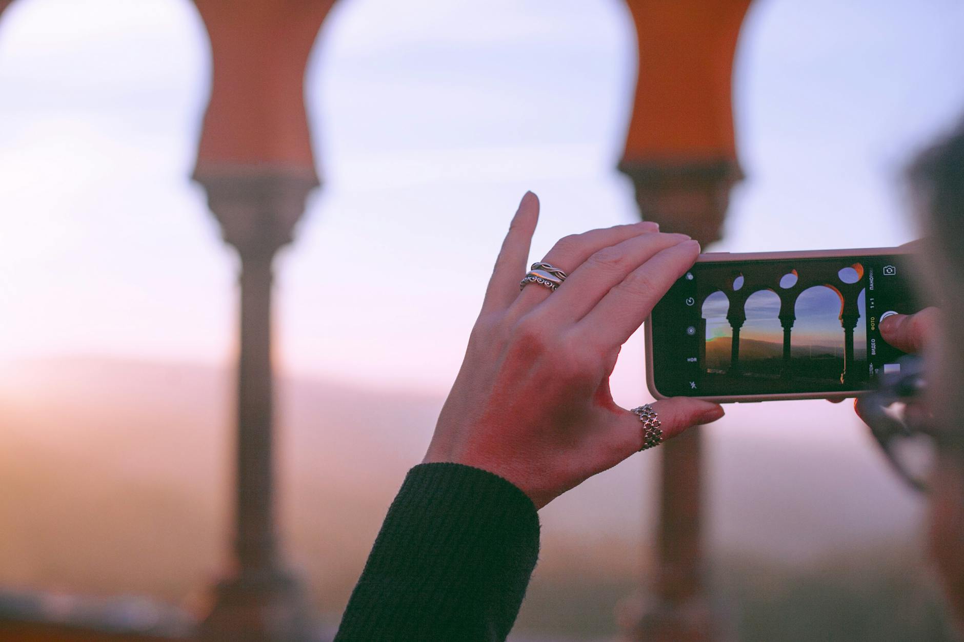 anonymous lady photographing arched palace at sundown