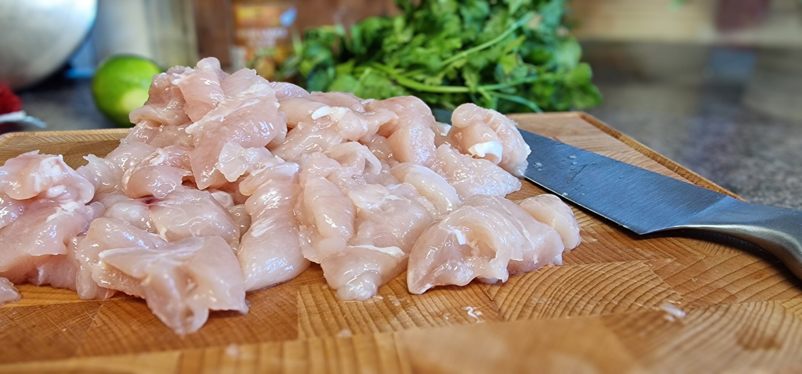 Chicken being cut into bite-sized pieces for satay chicken.