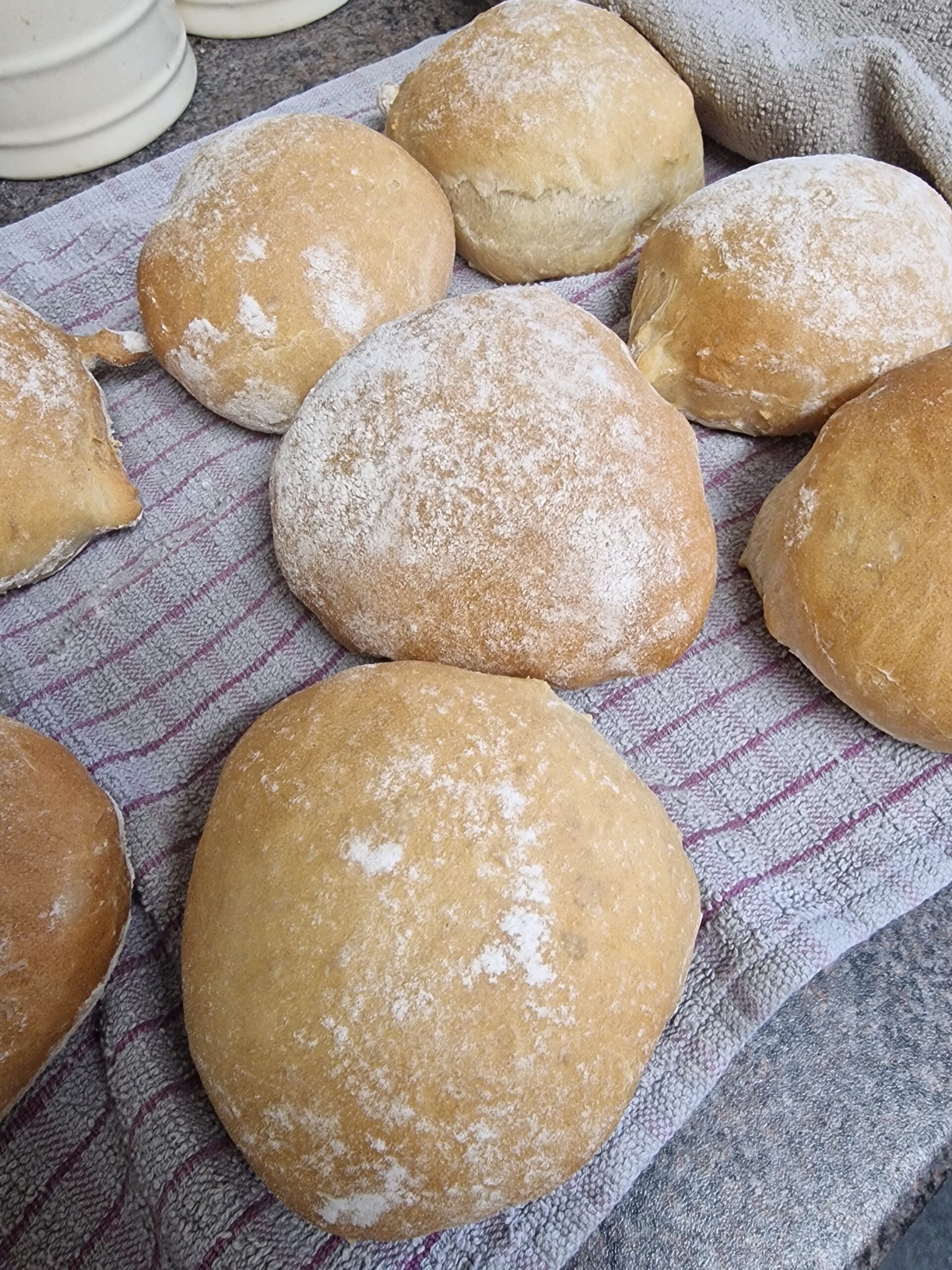 Soft bread rolls cooling on a tea towel.