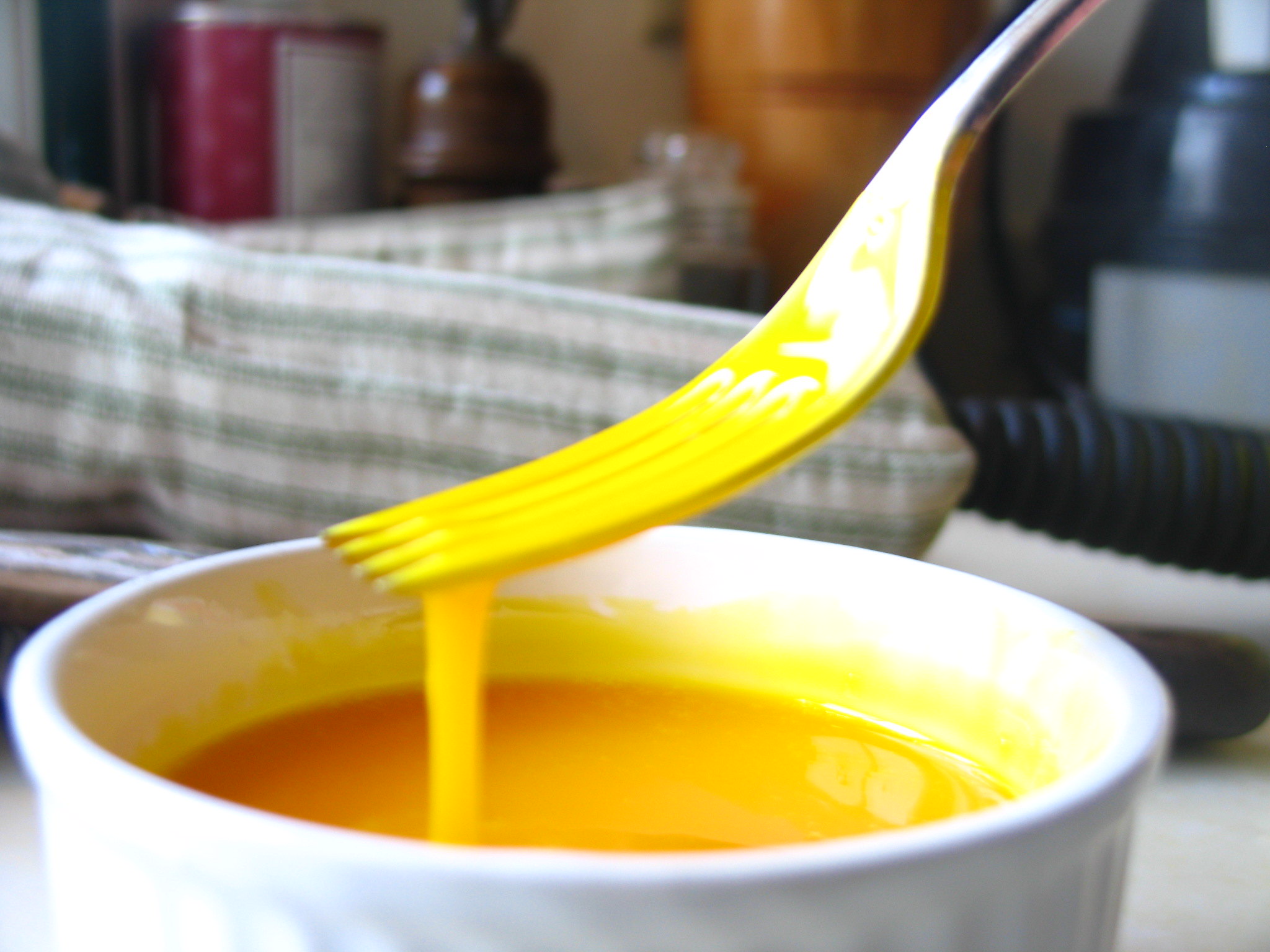 Hollandaise sauce being whisked in a metal bowl.