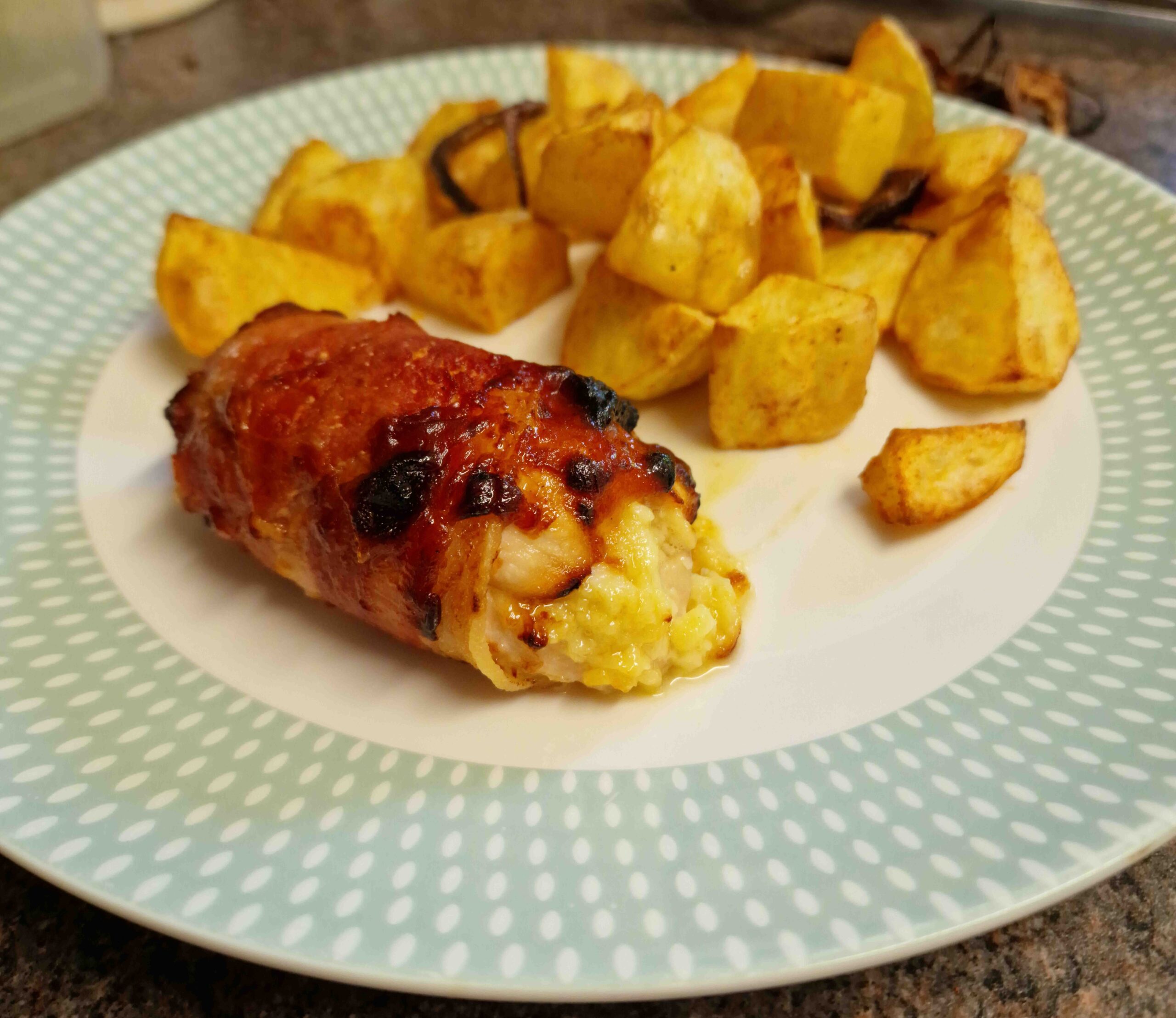 Bacon-wrapped honey-mustard stuffed chicken served with roast potatoes.